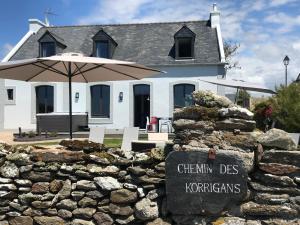 uma casa branca com um guarda-chuva e uma parede de pedra em Le Clos de la Pointe Saint-Mathieu em Plougonvelin