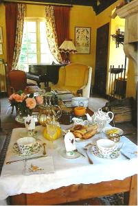 uma mesa com comida e um piano numa sala de estar em Le Petit Manoir des Bruyères em Villefargeau