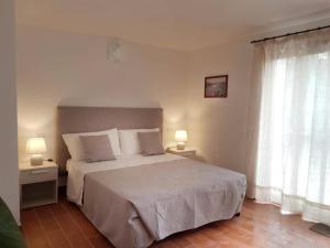 1 dormitorio con 1 cama, 2 lámparas y ventana en B&B Bell'alba en Santa Teresa Gallura