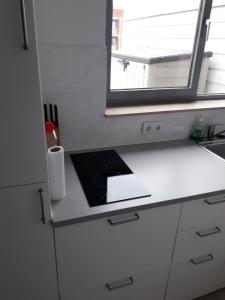 a white kitchen with a sink and a window at Dakstudio Met Reuze Zonneterras in Middelkerke