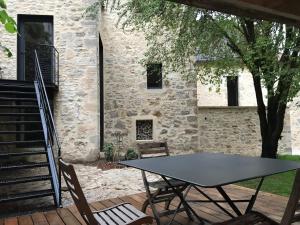 une table et des chaises devant un bâtiment en pierre dans l'établissement Les Jardins Sauvages, à Cabrerets