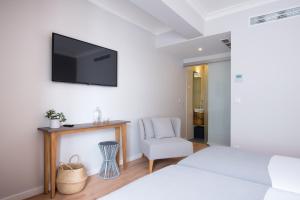 a bedroom with a tv on the wall and a chair at Reserva FLH Hotels Ericeira in Ericeira