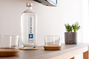 a bottle of water and two glasses on a table at Reserva FLH Hotels Ericeira in Ericeira