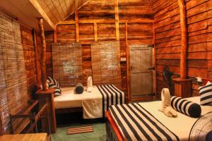 a bedroom with two beds in a room with wooden walls at Green Garden Resort in Habarana