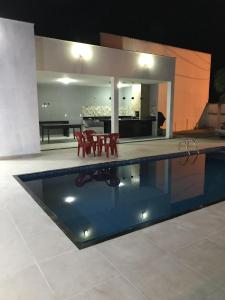 una piscina con sedie e tavolo in una casa di LINDA CASA NOVA VIÇOSA a Nova Viçosa