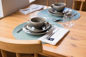 a wooden table with two cups and plates on it at Reserva FLH Hotels Ericeira in Ericeira