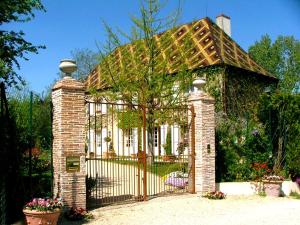 um portão em frente a uma casa com um telhado em Le Petit Manoir des Bruyères em Villefargeau