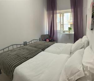 a bedroom with a bed with white sheets and a window at Santo Amaro Apartment in Lisbon