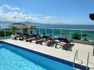 a swimming pool with chairs and a view of the ocean at Varadero Palace Hotel I in Florianópolis