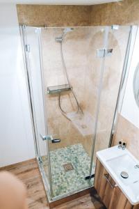 um chuveiro com uma porta de vidro ao lado de um lavatório em Adelheid Hotel garni em Quedlinburg