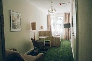 a living room with a table and a chair at Adelheid Hotel garni in Quedlinburg