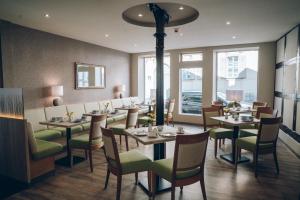 uma sala de jantar com mesas, cadeiras e janelas em Adelheid Hotel garni em Quedlinburg