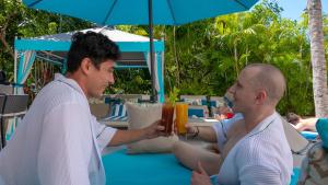 two men sitting at a table under an umbrella at Casa Cupula LGBT Luxury Resort in Puerto Vallarta