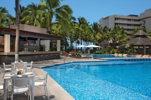 a pool at a resort with a table and chairs at Krystal Grand Nuevo Vallarta in Nuevo Vallarta 