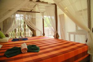 a bedroom with a bed with a striped bedspread and a window at Gihan Guesthouse in Mirissa