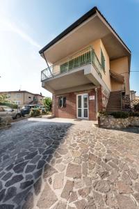 a house with a balcony on top of a stone driveway at MADI' casa vacanze in Laiatico