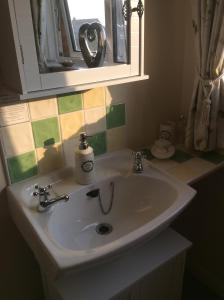 uma casa de banho com um lavatório, um espelho e uma janela em The Poplars em Newbold on Stour