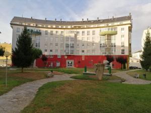 un grand bâtiment rouge et blanc avec un parc dans l'établissement JacobeAndo, à Sarria