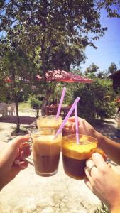 two people holding up two drinks with pink straws at family hotel our house in Ts'ikhisdziri