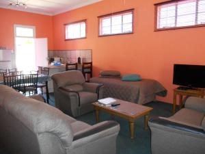 a living room with couches and chairs and a flat screen tv at Obesa Lodge in Graaff-Reinet