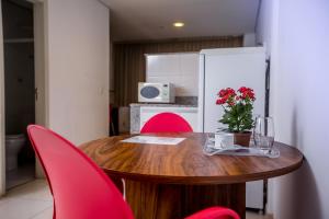 a dining room table with red chairs and a white refrigerator at Hotel Flat Itaipava in Itaipava