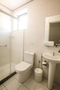 a white bathroom with a toilet and a sink at Hotel Flat Itaipava in Itaipava
