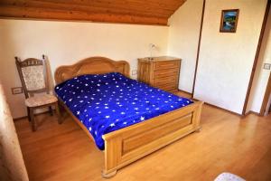 a bedroom with a bed with blue sheets and a dresser at Котедж Гірський in Yaremche