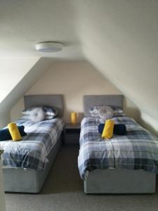 - 2 lits avec des oreillers jaunes dans une chambre mansardée dans l'établissement Mortlach Cottage, à Dufftown