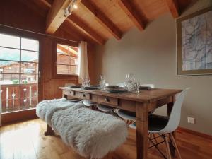 a dining room with a wooden table with a white rug at Mountain Village Chalet in Saas-Fee