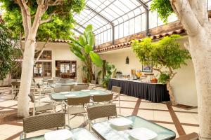 restauracja ze stołami i krzesłami oraz szklanym sufitem w obiekcie Clocktower Inn Ventura w mieście Ventura
