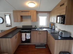 a small kitchen with wooden cabinets and a stove at Flamingo Land - Maple Grove MG32 in Kirby Misperton