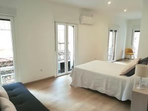 a white bedroom with a bed and a couch at Casón del Comercio in Toledo