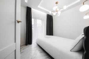 um quarto branco com uma cama e uma janela em Luxury Suites Kaunas, self-check in em Kaunas