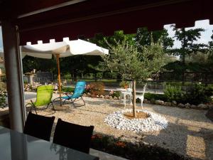 um pátio com 2 cadeiras, uma mesa e um guarda-sol em Ca' Pinetta em Rua di Feletto