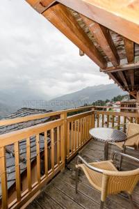 una terraza de madera con sillas y una mesa. en Les Chalets de Wengen - La Panoramique, en Les Coches