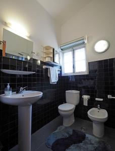 a bathroom with a sink and a toilet and a window at Casa do Sol in Moledo