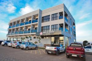 a building with cars parked in a parking lot at Hotel Ares do Sertão in Chapada Gaucha