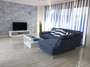 salon z niebieską kanapą i telewizorem w obiekcie Apartamenty Przy Latarni Kropla Bałtyku w Darłówku