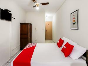 1 dormitorio con cama blanca y almohadas rojas en OYO Hotel Nobrega Aeroporto de Congonhas, São Paulo en São Paulo