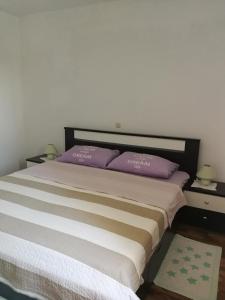 een slaapkamer met een groot bed met paarse kussens bij Apartments N&M in Sukošan