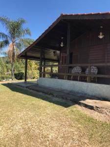 a brown building with a roof with a grass yard at Chacara estilo Chale in Roças Novas