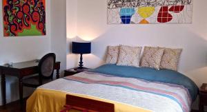 a bed in a bedroom with paintings on the wall at LE MASSITROU - chambre d'hôte - Table d'hôte in Nedde