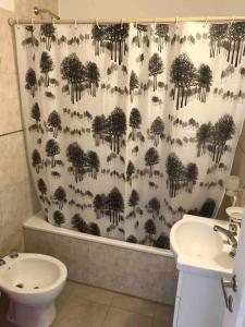 La salle de bains est pourvue d'un rideau de douche avec des arbres et de toilettes. dans l'établissement Vistas de la meseta Patagónica, à Trelew
