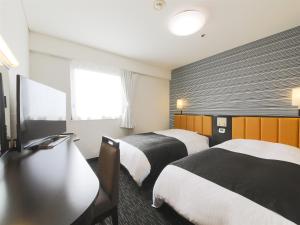 鶴岡市にあるアパホテル 山形鶴岡駅前のベッド2台とテレビが備わるホテルルームです。