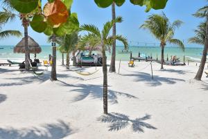 a beach with palm trees and people on the beach at Amaite Beach Hotel in Holbox Island