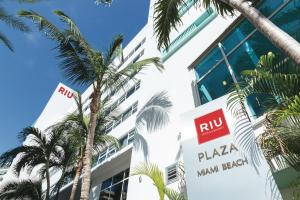a building with a pizza main break sign and palm trees at Riu Plaza Miami Beach in Miami Beach