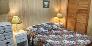 a bedroom with a bed with a floral bedspread and two lamps at Sunrise Resort in Buckhorn