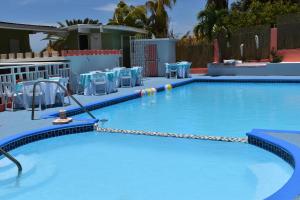 une grande piscine avec des tables et des chaises bleues dans l'établissement Posada del Mar, à La Parguera