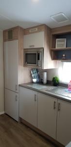 a kitchen with white cabinets and a microwave at dees hot tub breaks tattershall lakes The Ramparts 20 in Tattershall