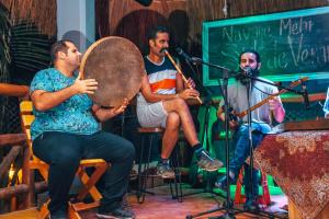 a group of men playing instruments on a stage at Tribu Hostel in Holbox Island